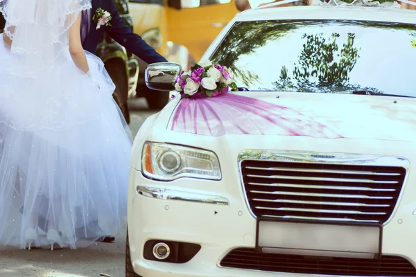 Ženich a nevěsta o svatební auto zdobené květinami a žebra — Stock fotografie