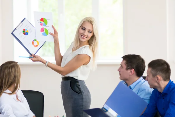 Team members listening attentively to a business woman holding a — Stock Photo, Image