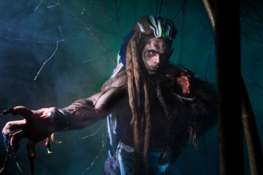 Muscular werewolf with dreadlocks with long nails among the bran
