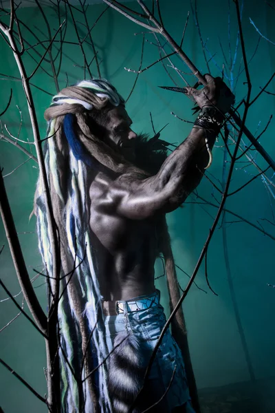 Portrait muscular werewolf with dreadlocks among the branches of — Stock Photo, Image