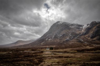 Glencoe 'da gökyüzü dramatik olan uzak bir kulübe.