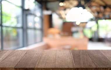 Restoranın soyut bulanık arka planının önündeki boş, siyah ahşap masa. Ürünlerinizi görüntülemek ya da montajlamak için kullanılabilir.