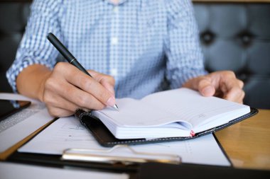 Erkek öğrenci, üniversite kampüsündeki derslere hazırlanırken taşınabilir tabletten bilgi yazar