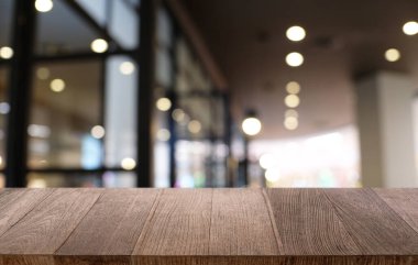 Restoranın soyut bulanık arka planının önündeki boş, siyah ahşap masa. Ürünlerinizi görüntülemek ya da montajlamak için kullanılabilir.