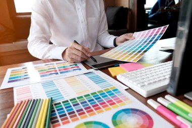 Grafik tasarımcısı dijital tablet üzerinde çalışıyor. Grafik tablet ve renk örneklerine resim çizen sanatçı