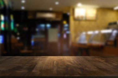 Kafenin soyut bulanık arka planının önündeki boş ahşap masa. Ürünlerinizi görüntülemek veya montajlamak için kullanılabilir. Ürünün görüntülenmesi için modelleyin.