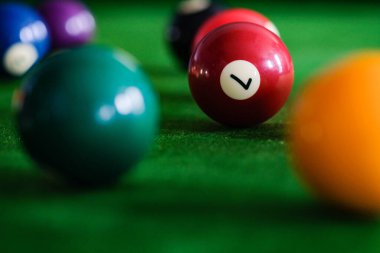 Adamın eli ve Cue kolu bilardo oynuyor ya da yeşil bir bilardo masasında bilardo topu fırlatmaya hazırlanıyor. Yeşil frizde renkli bilardo topları
