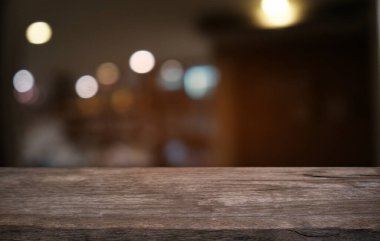 Restoranın soyut bulanık arka planının önündeki boş, siyah ahşap masa. Ürünlerinizi görüntülemek ya da montajlamak için kullanılabilir.