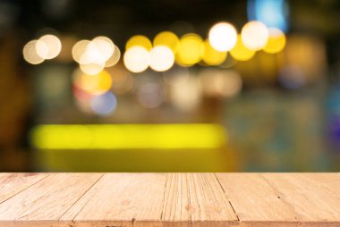 Bokeh ışığının bulanık arka planının önündeki boş ahşap masa. Ürünlerinizi görüntülemek veya montajlamak için kullanılabilir. Ürünün görüntülenmesi için modelleyin
