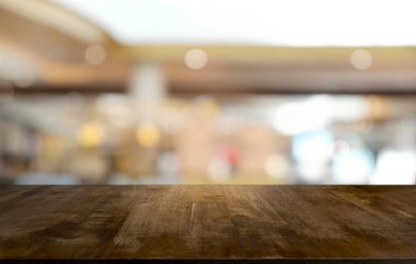 Restoranın soyut bulanık arka planının önündeki boş, siyah ahşap masa. Ürünlerinizi görüntülemek ya da montajlamak için kullanılabilir.