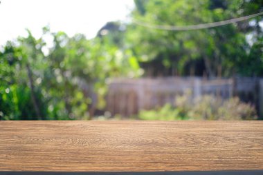 Açık hava bahçe ışıklarının soyut bulanık arka planının önündeki ahşap masa resmi. Ürünlerinizi görüntülemek veya montajlamak için kullanılabilir. Produc gösterimi için modelleyin