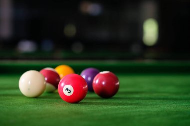 Adamın eli ve Cue kolu bilardo oynuyor ya da yeşil bir bilardo masasında bilardo topu fırlatmaya hazırlanıyor. Yeşil frizde renkli bilardo topları