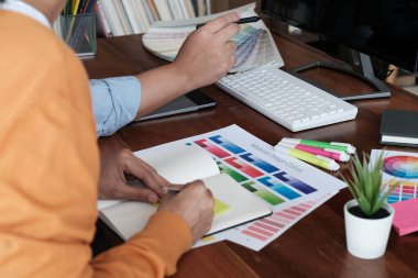 Grafik tasarımcısı dijital tablet üzerinde çalışıyor. Grafik tablet ve renk örneklerine resim çizen sanatçı