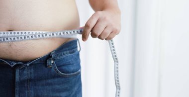 Diyet konseptinde şişman göbekli bir adam. Kilolu adam şişman karnına dokunuyor ve kilo vermek istiyor.