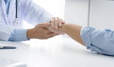 Doktorun hastasının elini tutması ve erkek hastasına el konseptine yardım etmesi.