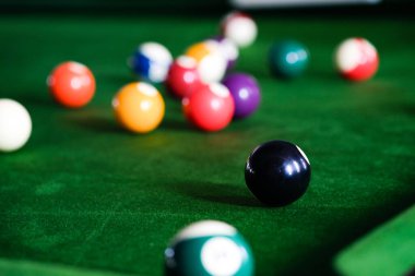Adamın eli ve Cue kolu bilardo oynuyor ya da yeşil bir bilardo masasında bilardo topu fırlatmaya hazırlanıyor. Yeşil frizde renkli bilardo topları