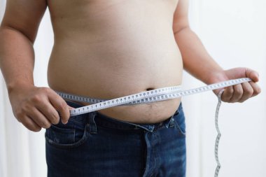 Diyet konseptinde şişman göbekli bir adam. Kilolu adam şişman karnına dokunuyor ve kilo vermek istiyor.