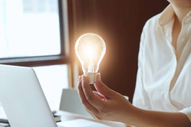 İş adamının ampul kavramını elinde tutması fikri ampullerle yaratıcılık