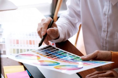 Grafik tasarımcısı dijital tablet üzerinde çalışıyor. Grafik tablet ve renk örneklerine resim çizen sanatçı