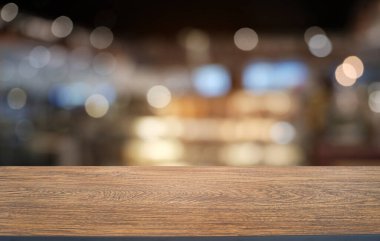 Restoranın soyut bulanık arka planının önündeki boş, siyah ahşap masa. Ürünlerinizi görüntülemek ya da montajlamak için kullanılabilir. 