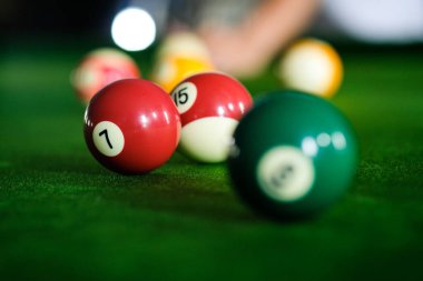 Adamın eli ve Cue kolu bilardo oynuyor ya da yeşil bir bilardo masasında bilardo topu fırlatmaya hazırlanıyor. Yeşil frizde renkli bilardo topları