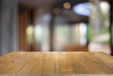 Kafenin soyut bulanık arka planının önündeki boş, siyah ahşap masa. Ürünlerinizi görüntülemek veya montajlamak için kullanılabilir. Ürünün görüntülenmesi için modelleyin.