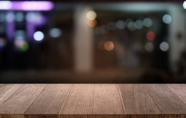 Restoranın soyut bulanık arka planının önündeki boş, siyah ahşap masa. Ürünlerinizi görüntülemek ya da montajlamak için kullanılabilir. 