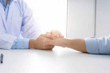 Doktorun hastasının elini tutması ve erkek hastasına el konseptine yardım etmesi.