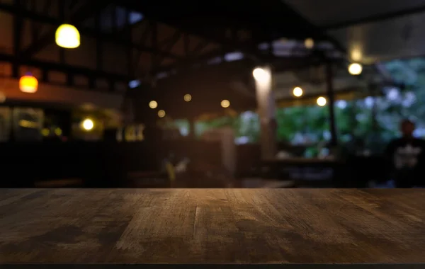 Restoranın soyut bulanık arka planının önündeki boş, siyah ahşap masa. Ürünlerinizi görüntülemek ya da montajlamak için kullanılabilir.
