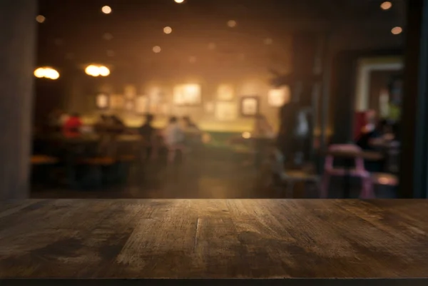 Restoranın soyut bulanık arka planının önündeki boş, siyah ahşap masa. Ekran ürünleri için kullanılabilir. Boşluk için ayarlayın.