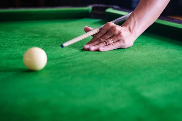 Man\'s hand and Cue arm playing snooker game or preparing aiming to shoot pool balls on a green billiard table. Colorful snooker balls on green frieze