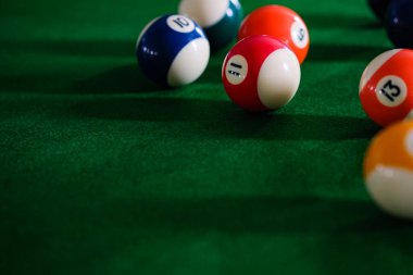 Adamın eli ve Cue kolu bilardo oynuyor ya da yeşil bir bilardo masasında bilardo topu fırlatmaya hazırlanıyor. Yeşil frizde renkli bilardo topları