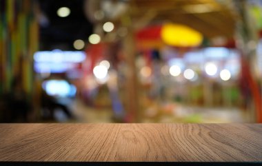 Restoranın soyut bulanık arka planının önündeki boş, siyah ahşap masa. Ürünlerinizi görüntülemek ya da montajlamak için kullanılabilir.