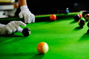 Adamın eli ve Cue kolu bilardo oynuyor ya da yeşil bir bilardo masasında bilardo topu fırlatmaya hazırlanıyor. Yeşil frizde renkli bilardo topları