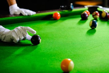 Adamın eli ve Cue kolu bilardo oynuyor ya da yeşil bir bilardo masasında bilardo topu fırlatmaya hazırlanıyor. Yeşil frizde renkli bilardo topları