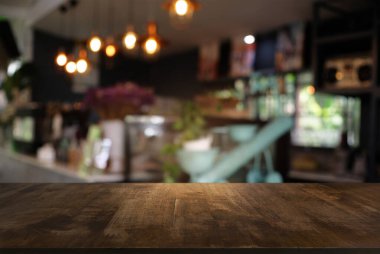 Kafenin soyut bulanık arka planının önündeki boş ahşap masa. Ürünlerinizi görüntülemek veya montajlamak için kullanılabilir. Ürünün görüntülenmesi için modelleyin