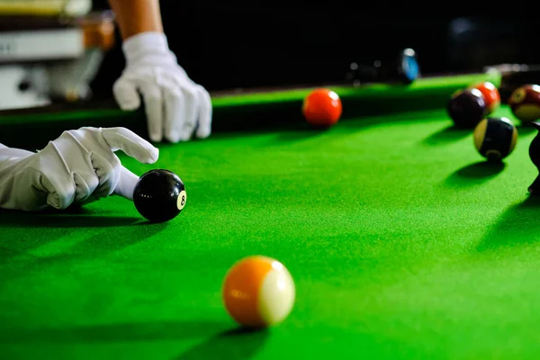 Adamın eli ve Cue kolu bilardo oynuyor ya da yeşil bir bilardo masasında bilardo topu fırlatmaya hazırlanıyor. Yeşil frizde renkli bilardo topları
