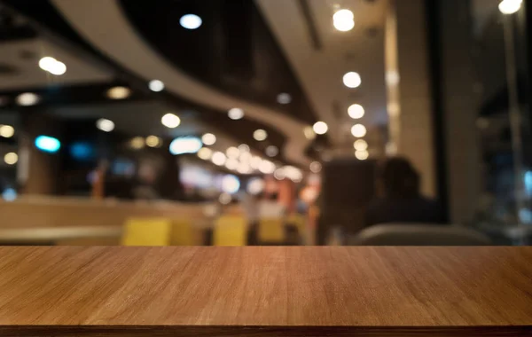 Empty dark wooden table in front of abstract blurred bokeh background of restaurant . can be used for display or montage your products.Mock up for space