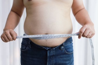 Diyet konseptinde şişman göbekli bir adam. Kilolu adam şişman karnına dokunuyor ve kilo vermek istiyor.