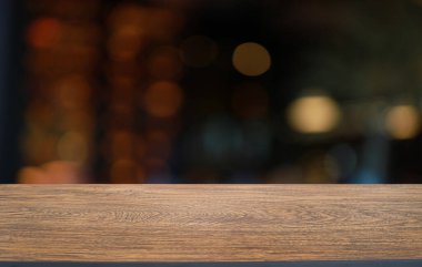 Kafenin soyut bulanık arka planının önündeki boş ahşap masa. Öndeki ahşap tablo ürünlerinizi görüntülemek veya montajlamak için kullanılabilir. Produc gösterimi için modelleyin