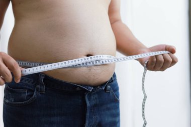 Diyet konseptinde şişman göbekli bir adam. Kilolu adam şişman karnına dokunuyor ve kilo vermek istiyor.