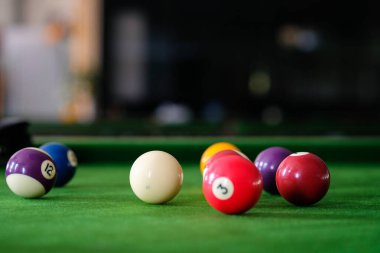 Adamın eli ve Cue kolu bilardo oynuyor ya da yeşil bir bilardo masasında bilardo topu fırlatmaya hazırlanıyor. Yeşil frizde renkli bilardo topları