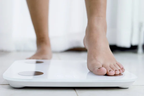 feet standing on electronic scales for weight control. Measurement instrument in kilogram for a diet control