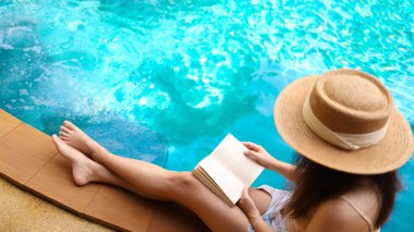 Yaz tatili genç Asyalı güzel kadın spa merkezinde havuzda dinleniyor. Yüzme havuzlu güzel bir tropik plaj oteli.