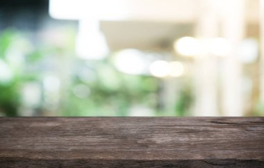 Kafenin soyut bulanık arka planının önündeki boş ahşap masa. Öndeki ahşap tablo ürünlerinizi görüntülemek veya montajlamak için kullanılabilir. Produc gösterimi için modelleyin