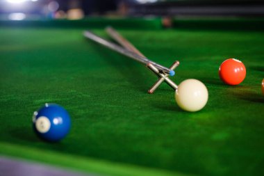 Adamın eli ve Cue kolu bilardo oynuyor ya da yeşil bir bilardo masasında bilardo topu fırlatmaya hazırlanıyor. Yeşil frizde renkli bilardo topları