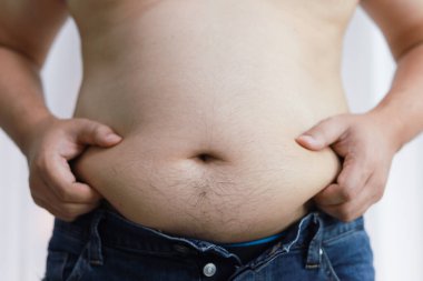 Diyet konseptinde şişman göbekli bir adam. Kilolu adam şişman karnına dokunuyor ve kilo vermek istiyor.