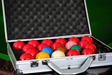 Adamın eli ve Cue kolu bilardo oynuyor ya da yeşil bir bilardo masasında bilardo topu fırlatmaya hazırlanıyor. Yeşil frizde renkli bilardo topları