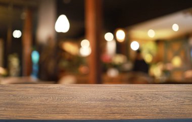 Kafenin soyut bulanık arka planının önündeki boş ahşap masa. Öndeki ahşap tablo ürünlerinizi görüntülemek veya montajlamak için kullanılabilir. Produc gösterimi için modelleyin