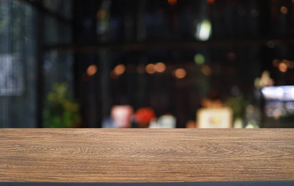 Empty wooden table in front of abstract blurred background of coffee shop . wood table in front can be used for display or montage your products.Mock up for display of produc